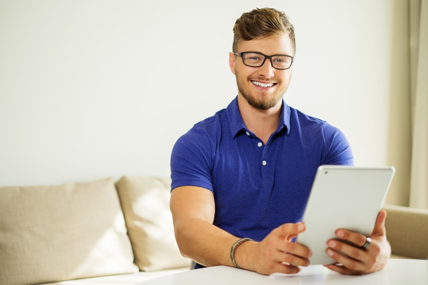 Handsome man using tablet pc at home  - Photo, image