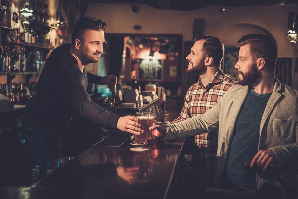 vrienden drinken tapbier op toog in pub. - Foto, afbeelding