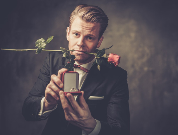 Άνθρωπος που κρατά το κουτί με μια πρόταση δαχτυλίδι και το κόκκινο τριαντάφυλλο - Φωτογραφία, εικόνα