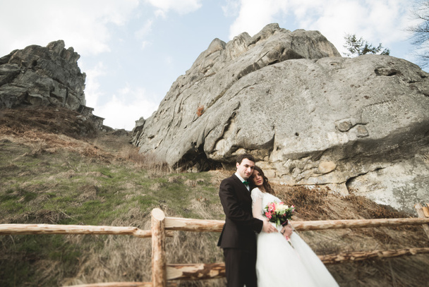 Happy wedding couple kissing and hugging near a high cliff - Fotografie, Obrázek