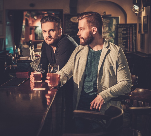 friends drinking draft beer at bar counter in pub. - Fotó, kép