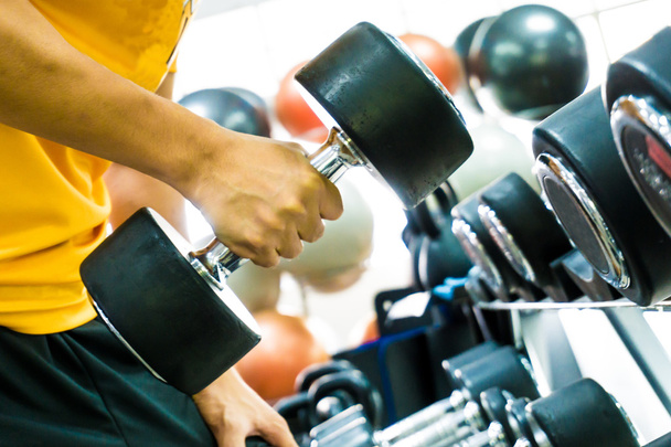 Bras de l'homme soulevant des poids et faisant de l'exercice dans un studio de fitness - Photo, image