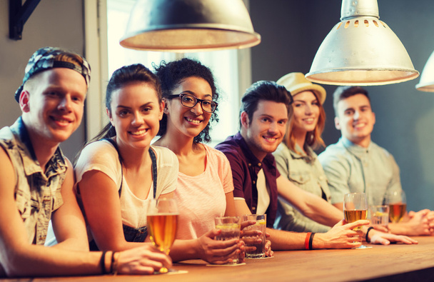 happy friends drinking beer and cocktails at bar - Φωτογραφία, εικόνα