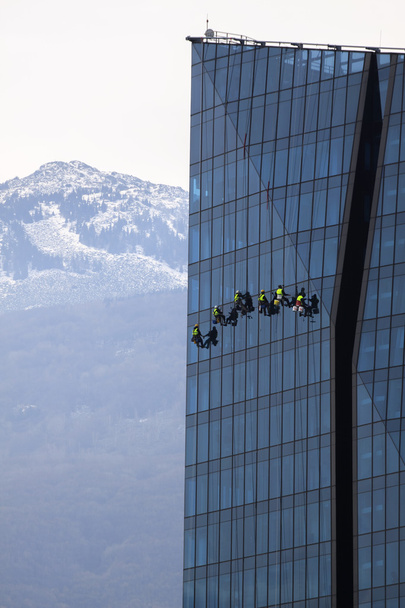 Seis alpinistas lavam janelas e fachada de vidro do arranha-céu
 - Foto, Imagem