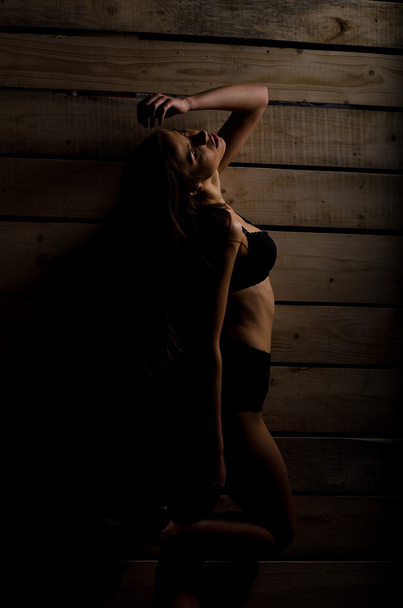 όμορφη σέξι κορίτσι σε ένα μαύρο μαγιό σε φόντο γυαλισμένο σανίδων - Φωτογραφία, εικόνα