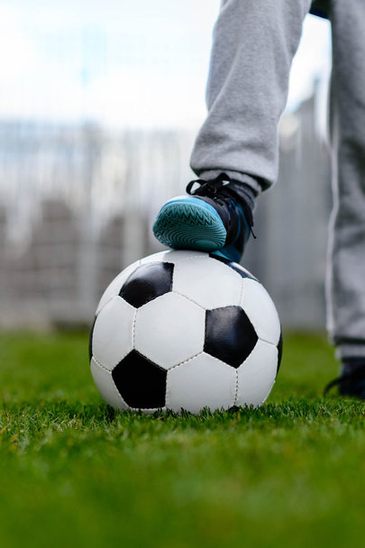 Ноги мальчика на мяче на футбольном поле
 - Фото, изображение