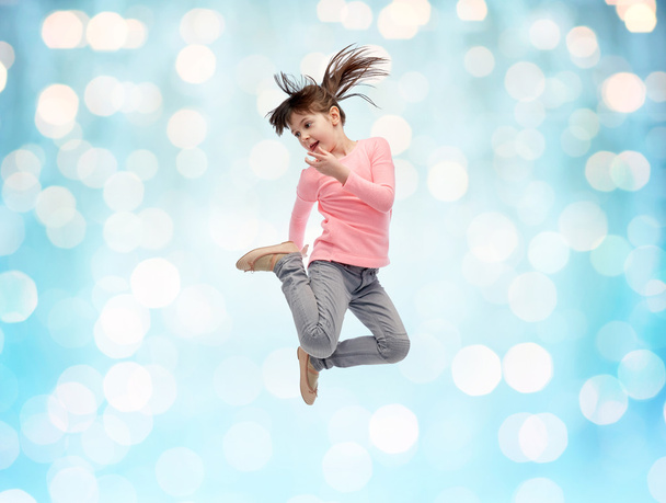 happy little girl jumping in air over blue lights - Foto, Imagem