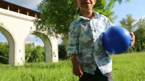 Boy with ball walks on grass  - Filmati, video
