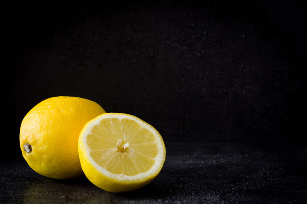 Lemons on black stone background - Фото, изображение