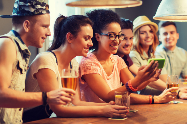 happy friends with smartphone taking selfie at bar - Foto, Bild