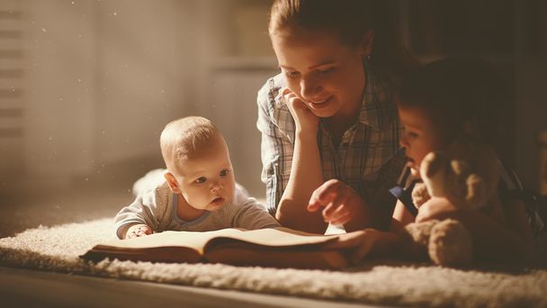 heureux famille mère et enfants lire un livre dans la soirée
 - Photo, image