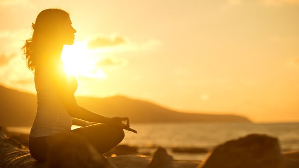 woman meditating in lotus pose on beach at sunset - Photo, Image