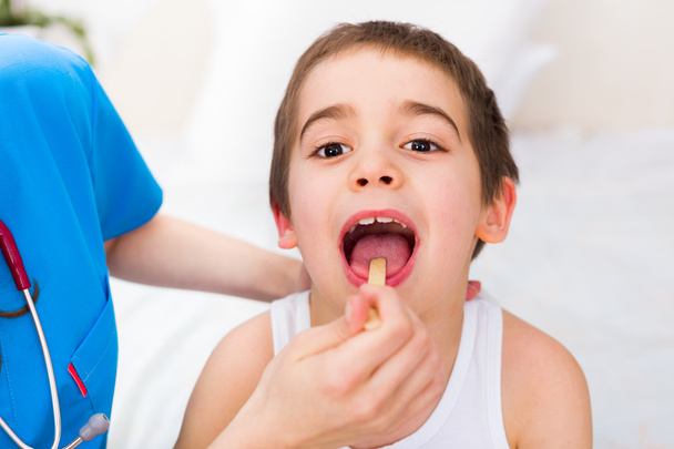 Pediatrician examining little boys throat - 写真・画像