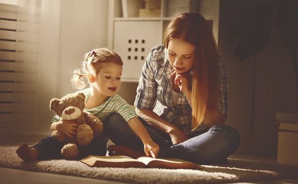 heureux famille mère et fille lire un livre dans la soirée
 - Photo, image