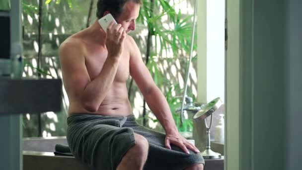 man talking on cellphone in the bathroom - Filmati, video