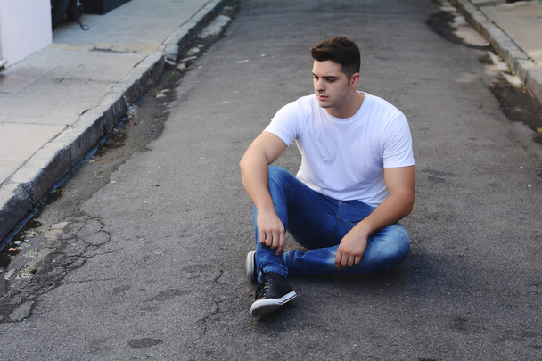 Young latin man sitting at the street - Фото, зображення