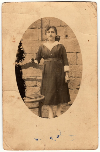 Foto vintage mostra mulher posa ao lado da cadeira histórica. Antique foto em preto e branco tem forma oval
. - Foto, Imagem