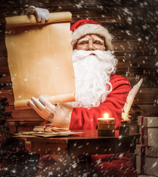 Santa Claus en casa de madera lectura interior lista de deseos scroll
 - Foto, Imagen