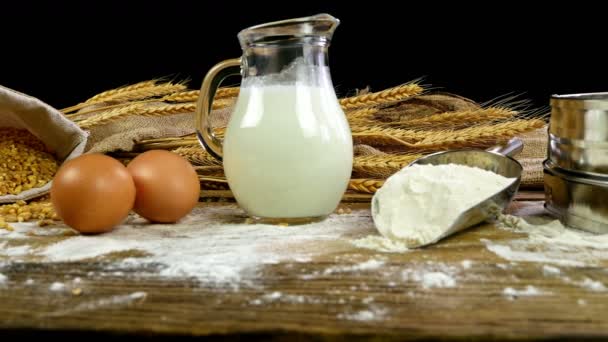 Tarwe, meel, melk, eieren en boter op een houten tafel, dolly, bovenaanzicht - Video