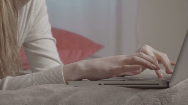 Close up of female hands typing on computer while lying on bed. - Кадри, відео