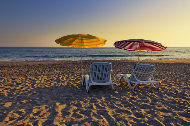 Due sedie vuote sotto ombrelloni su una spiaggia sabbiosa in estate
 - Foto, immagini