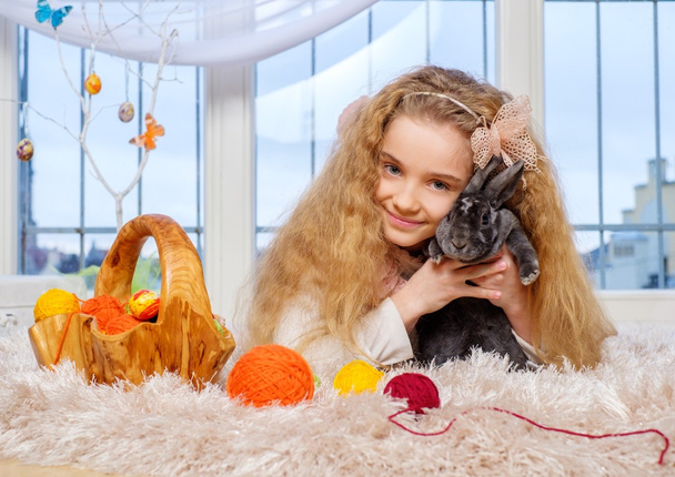 schöne kleine Mädchen sitzt auf Teppich und spielt mit niedlichen Hasen. - Foto, Bild