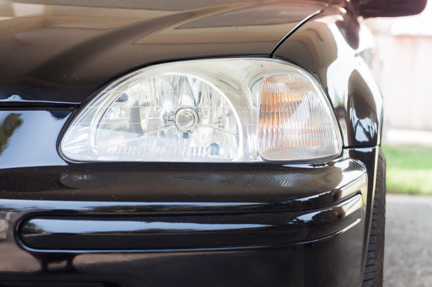 Closeup headlight of black coupe - Foto, afbeelding
