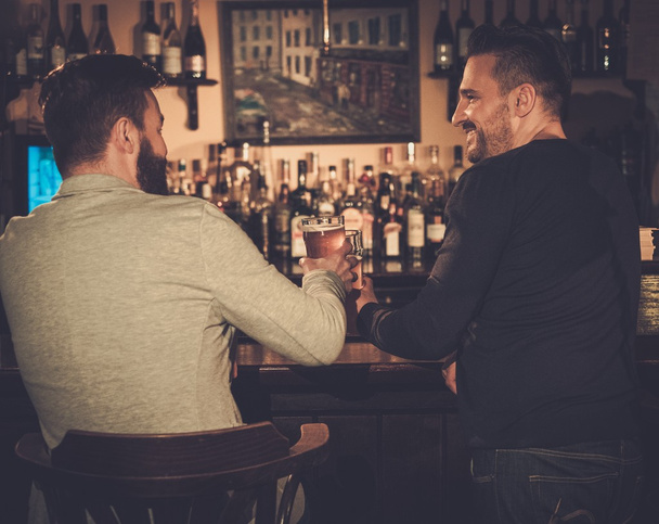 друзья пьют пиво в баре в пабе
. - Фото, изображение