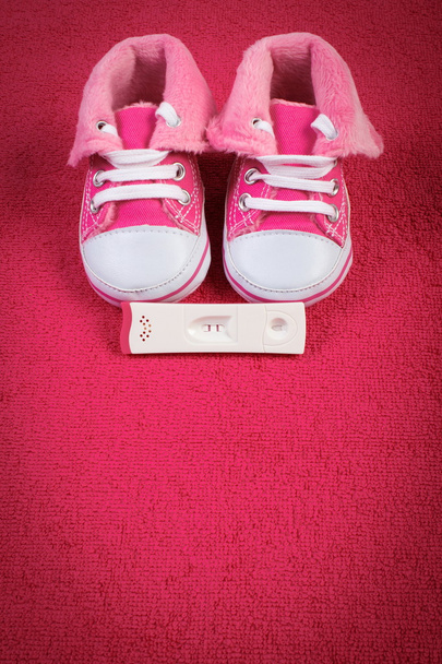 Pregnancy test with positive result and baby shoes on fluffy towel, expecting for baby, copy space for text - Foto, imagen