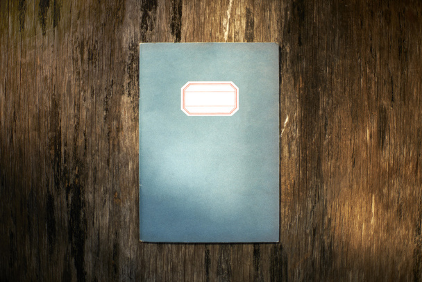 Cuaderno clásico sobre placa de madera en iluminación dramática
 - Foto, imagen