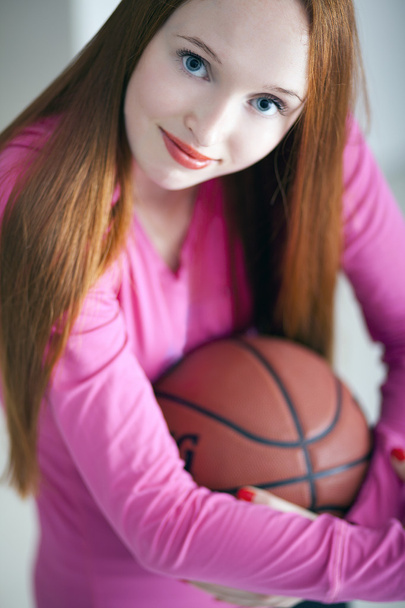 Hermosa chica de pelo largo sosteniendo una bola de canasta y sentado
 - Foto, imagen