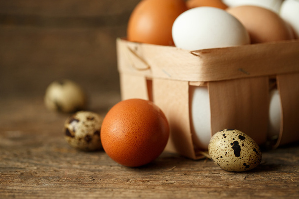 Verse kip en kwartel eieren op een houten achtergrond - Foto, afbeelding