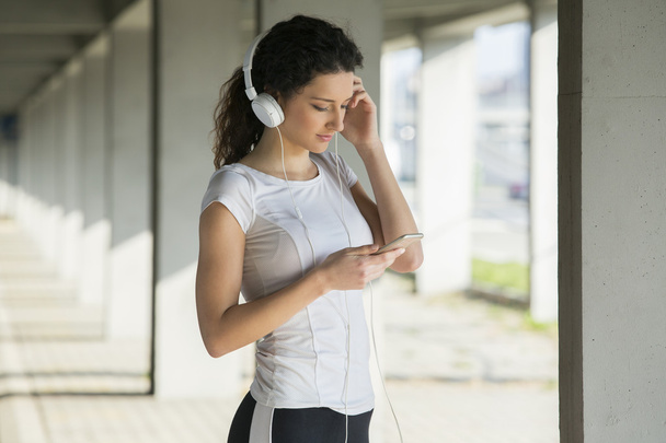 Fitness girl listening to music between workouts - Fotografie, Obrázek