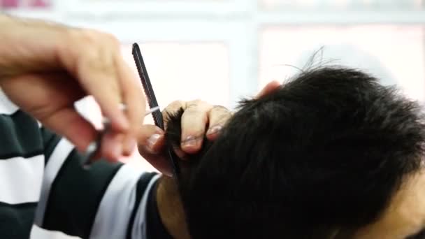 Peluquero acortando el pelo del niño con el cortador eléctrico y tijeras
 - Metraje, vídeo