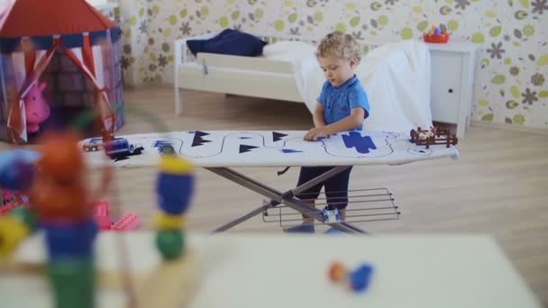 Μικρό σγουρά-με επικεφαλής αγόρι που παίζουν με τα παιχνίδια στο δωμάτιο - Πλάνα, βίντεο