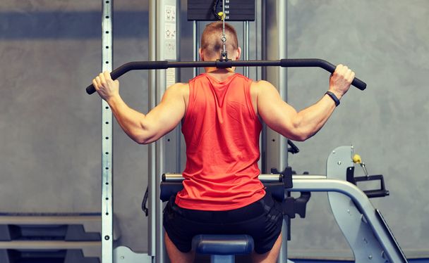 man flexing muscles on cable machine gym - 写真・画像