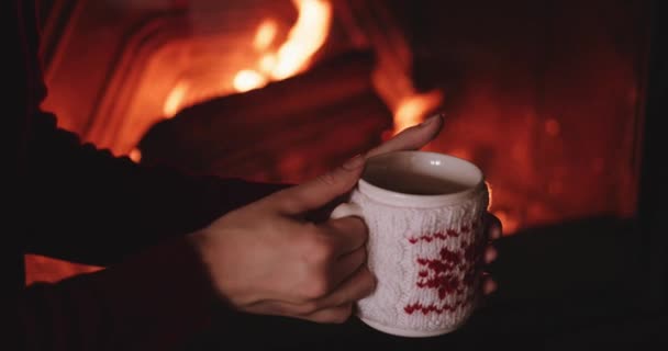Kobieta z kubkiem gorącej herbaty w pobliżu kominek - Materiał filmowy, wideo