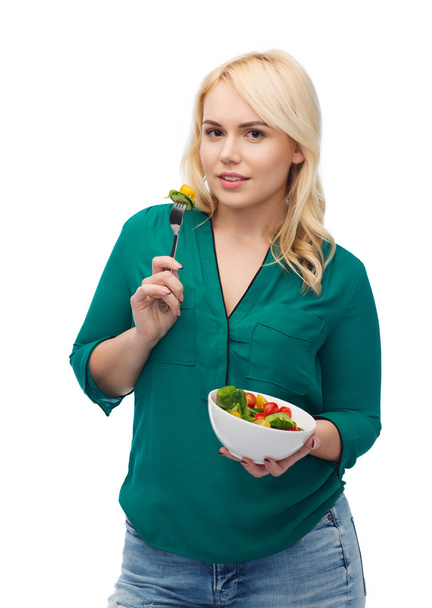 smiling young woman eating vegetable salad - Foto, afbeelding