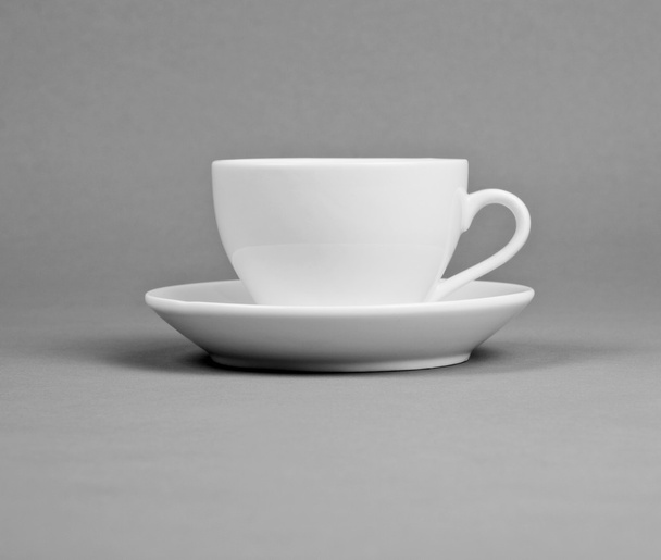 White mug and saucer on a gray background. - Фото, изображение