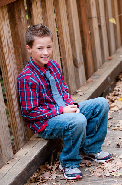 Portrait of cute boy sitting next to bridge outdoors. - Foto, imagen