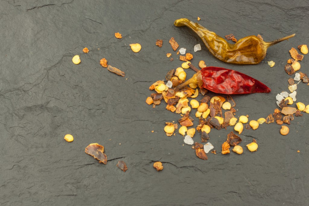 Dried chili peppers on dark slate. Strong spices for spicy foods. Decorate the kitchen. Place for your text. Creating the menu. - Photo, Image