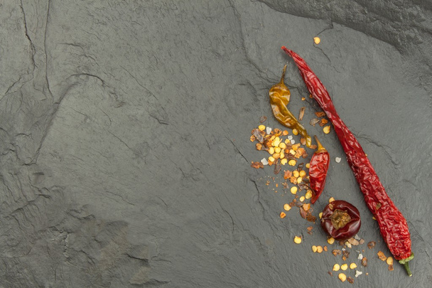 Dried chili peppers on dark slate. Strong spices for spicy foods. Decorate the kitchen. Place for your text. Creating the menu. - Photo, Image