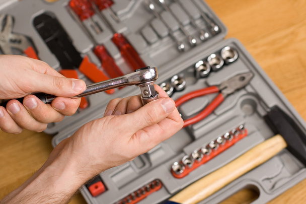 Hands holding ratchet and head over toolbox - Photo, Image