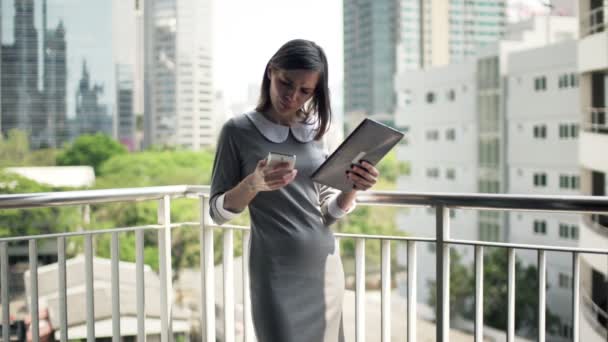 Businesswoman comparing data on tablet computer and smartphone - Footage, Video