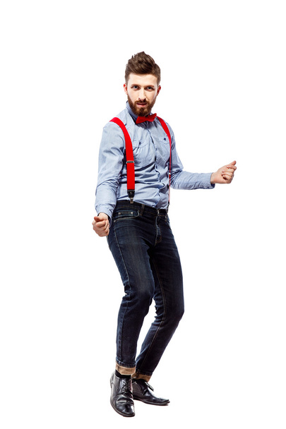 stylish guy in the blue shirt with red bowtie and suspenders isolated on white. dancing, clicking fingers. - Фото, изображение