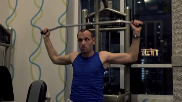 man exercising on lat machine in gym  - Materiał filmowy, wideo