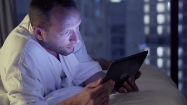 man watching movie on tablet computer on bed  - Felvétel, videó