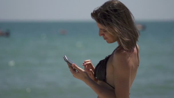 pretty woman using smartphone on beach - Materiał filmowy, wideo
