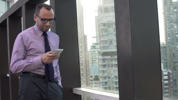 businessman using smartphone standing on terrace - Filmmaterial, Video