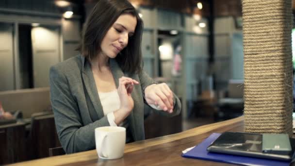 young businesswoman with smartwatch sitting in cafe - Filmmaterial, Video